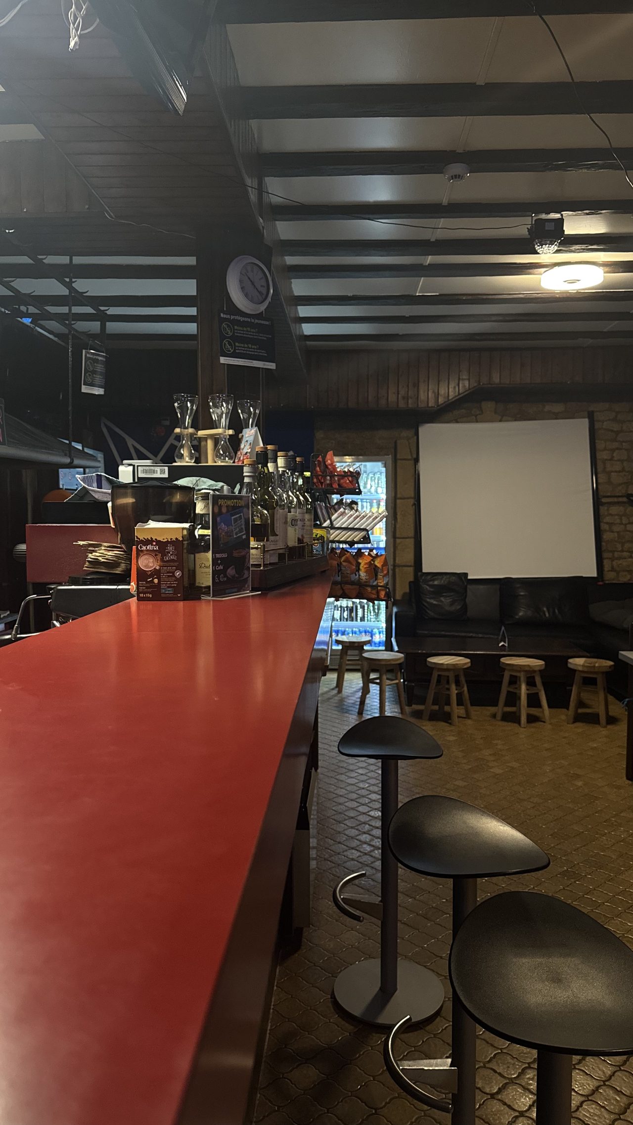 Vue en perspective du comptoir rouge avec tabourets et écran de projection